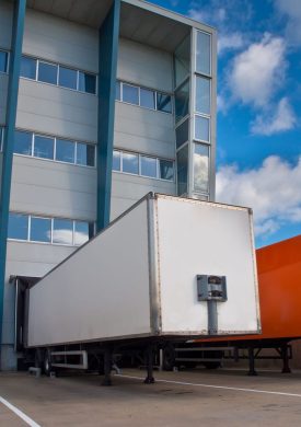 Distribution Center with Trailers Red and White Trailer in Front of Docking Bay ready for Transport